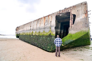 A man stands in front of a "Mulberry" at the artificial harbor at Arromanches.