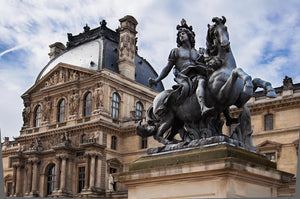 A statue of a French king riding a horse outside of the Louvre in Paris.