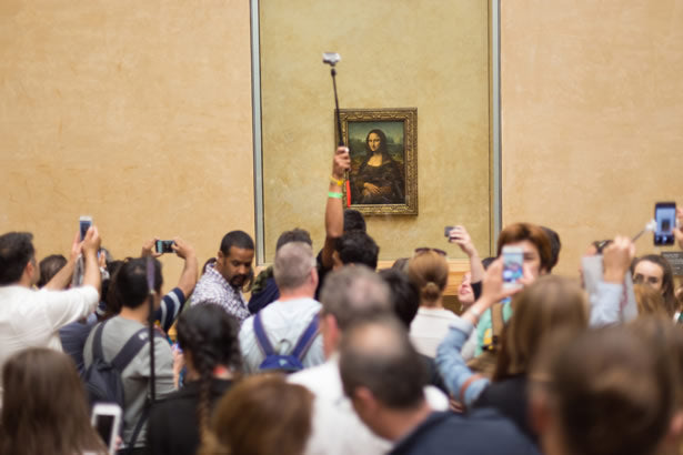 Tourists taking selfies in front of the Mona Lisa.