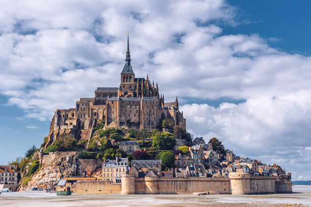 Historic Mont St. Michel abbey from across the flats in Normandy, France.