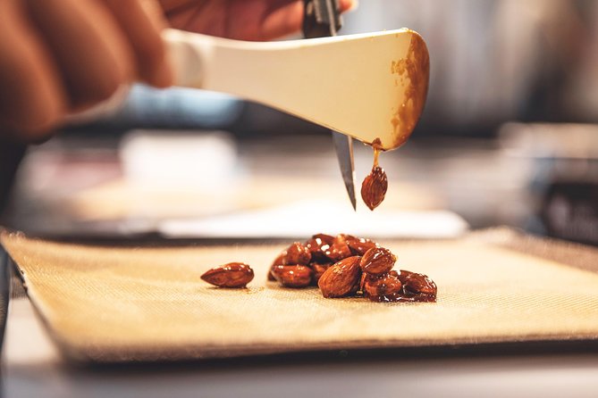 Candied almonds drop onto a silicon mat.